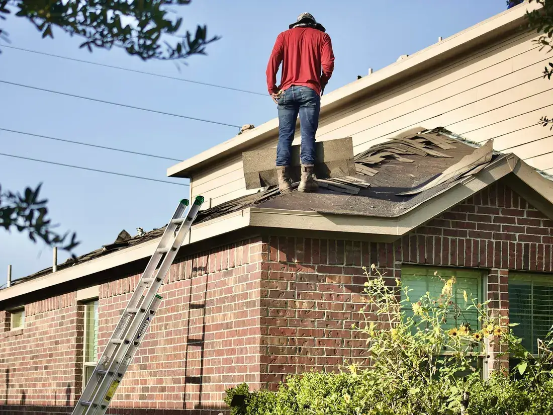 A Ridgeline roofer at work on the roof of a brick house