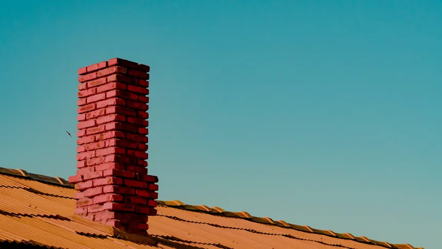 A brick chimney rising from a tiled roof on a Collier Row home