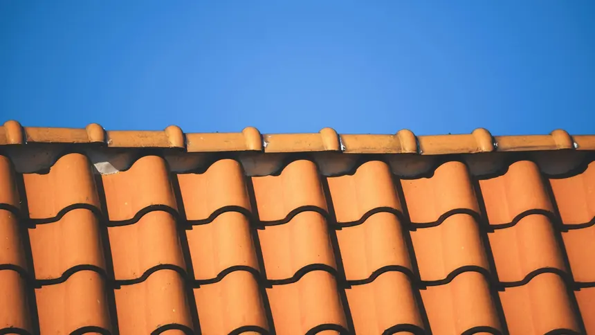 Neat rows of orange clay pantiles on an Upminster roof against a bright blue sky