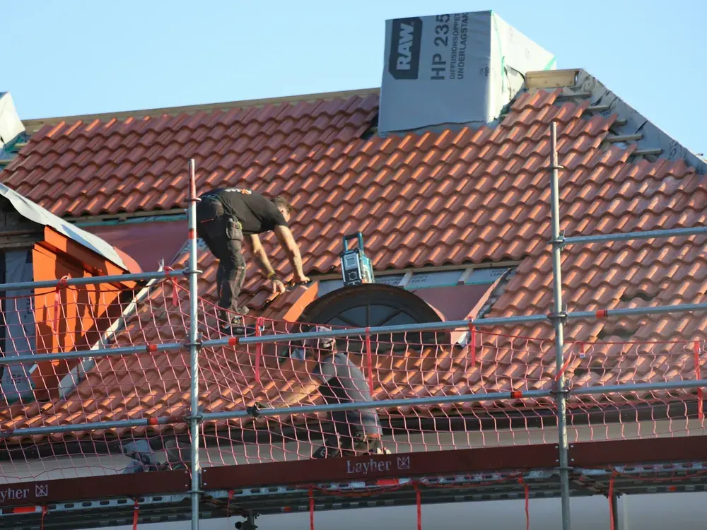 A Ridgeline roofer working on a tiled roof from a scaffold